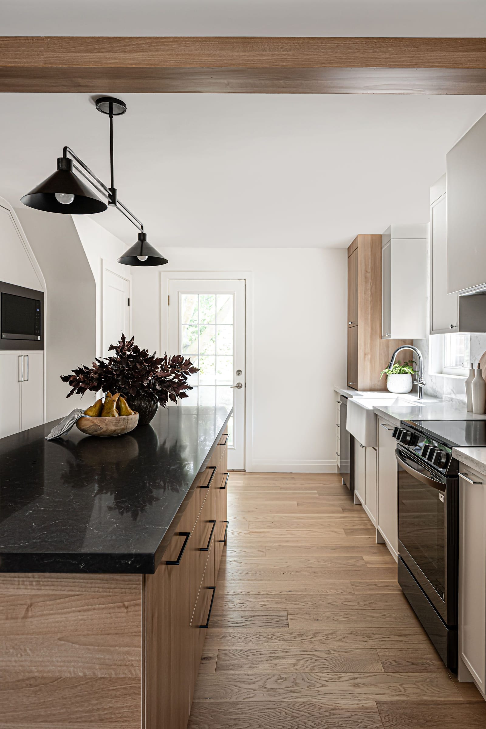 A long view down the kitchen between the island and the range wall to a back door with a window