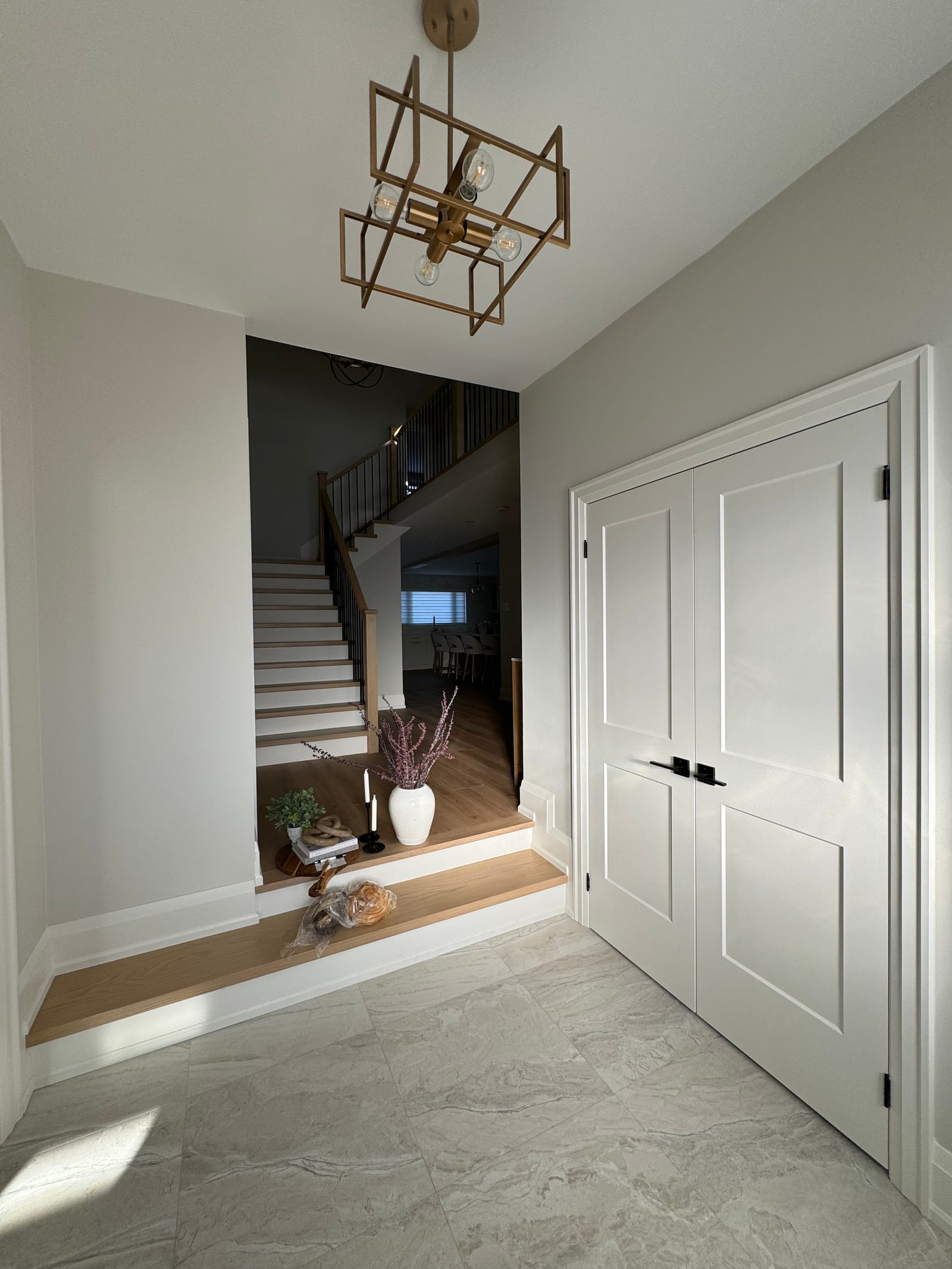 A tiled entry with white double closet doors and steps up to the stair