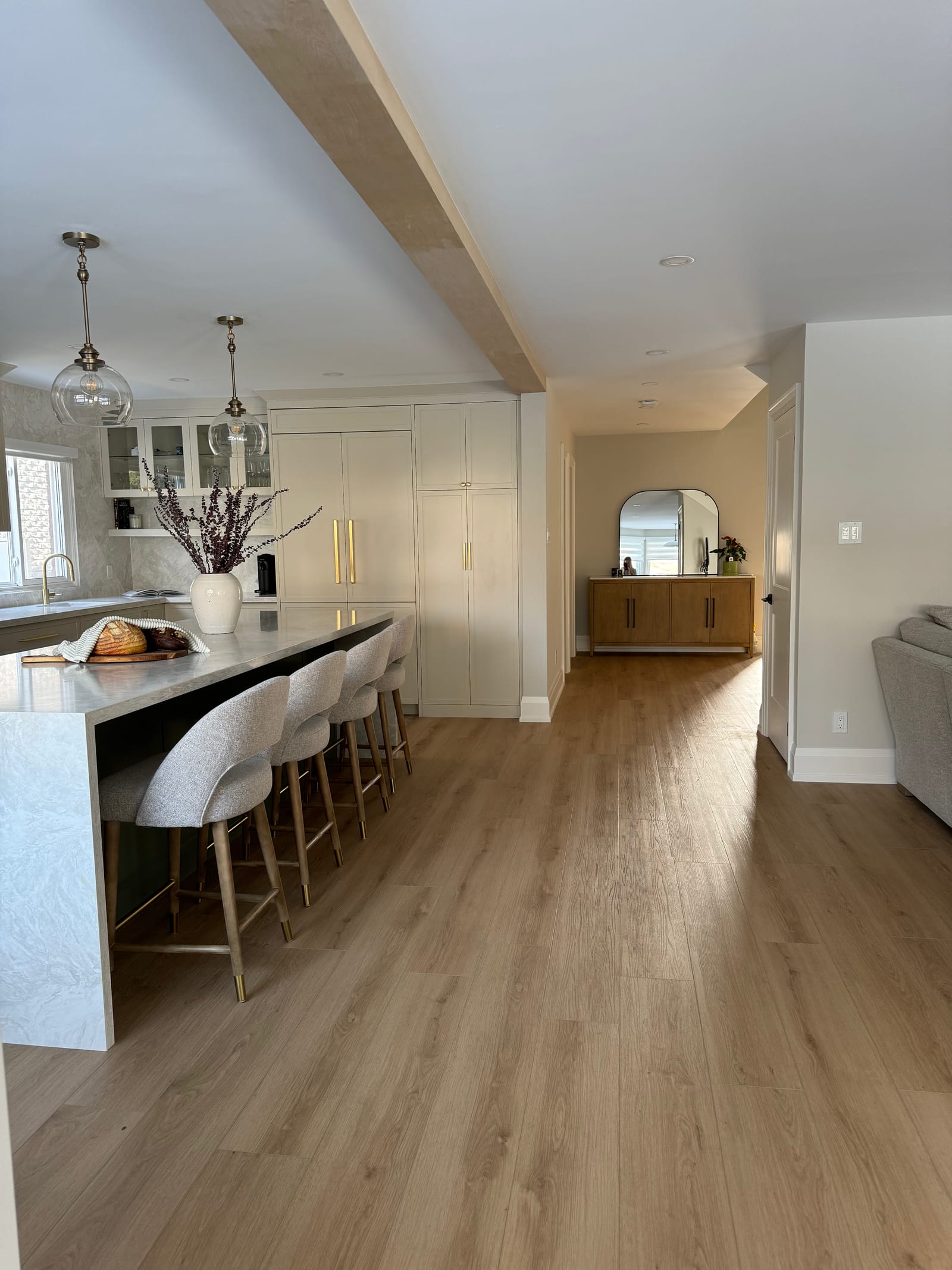The waterfall island and stools, with a long hall and an oak beam running toward the front door