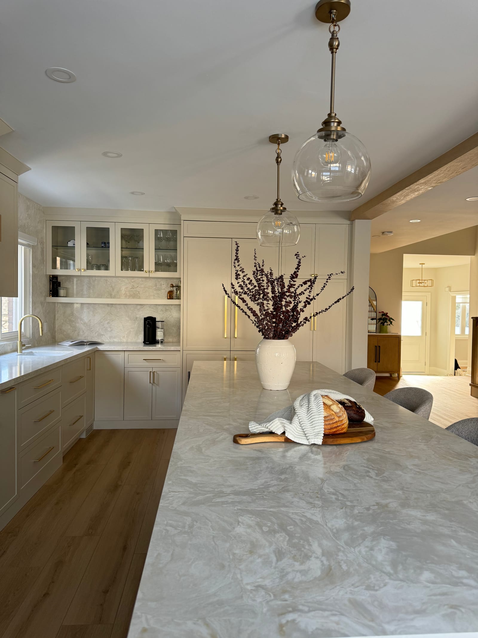 Close view of the stone island top under glass pendants, with glass-front cabinets beyond