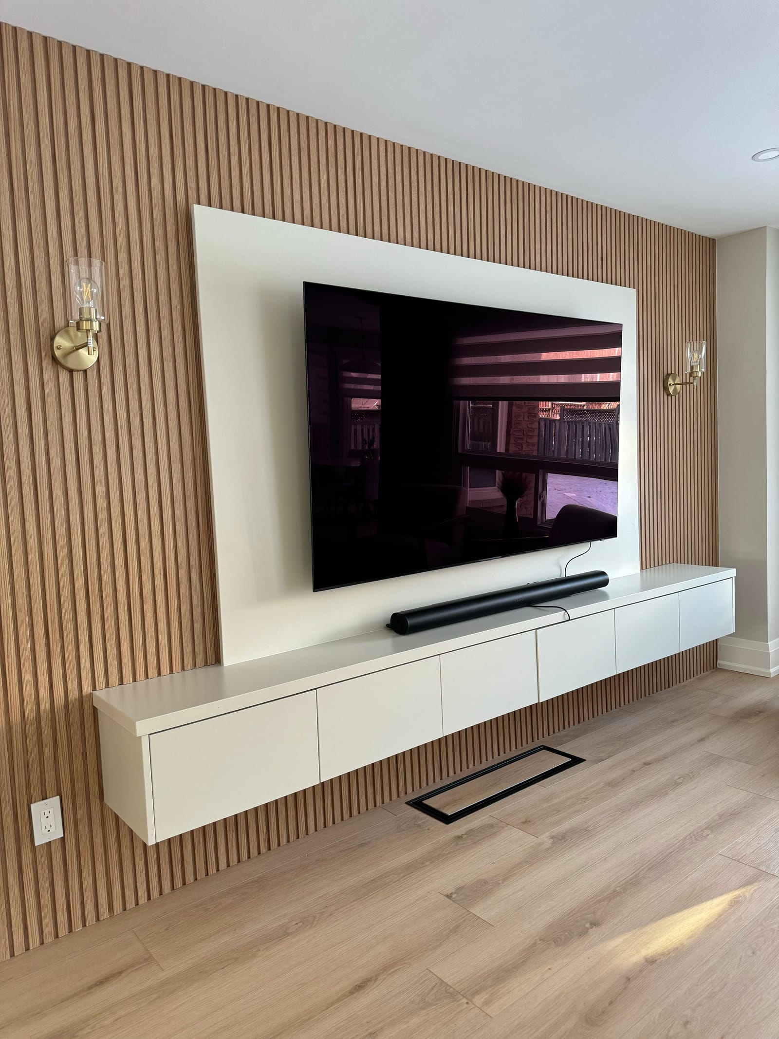 Angled view of the oak slat wall, white panel and floating cabinet