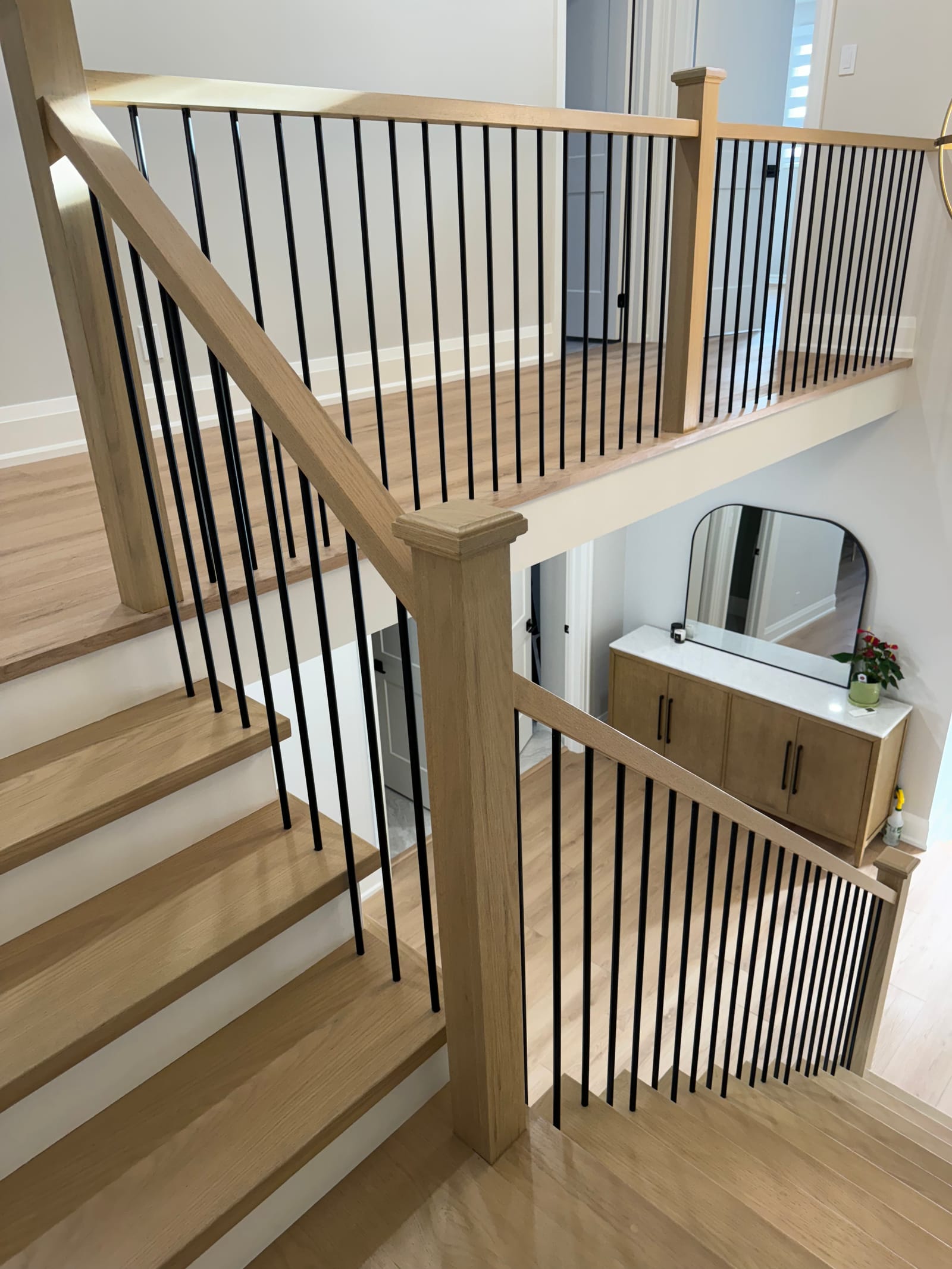 An oak staircase with square newels and black spindles, looking down to a landing