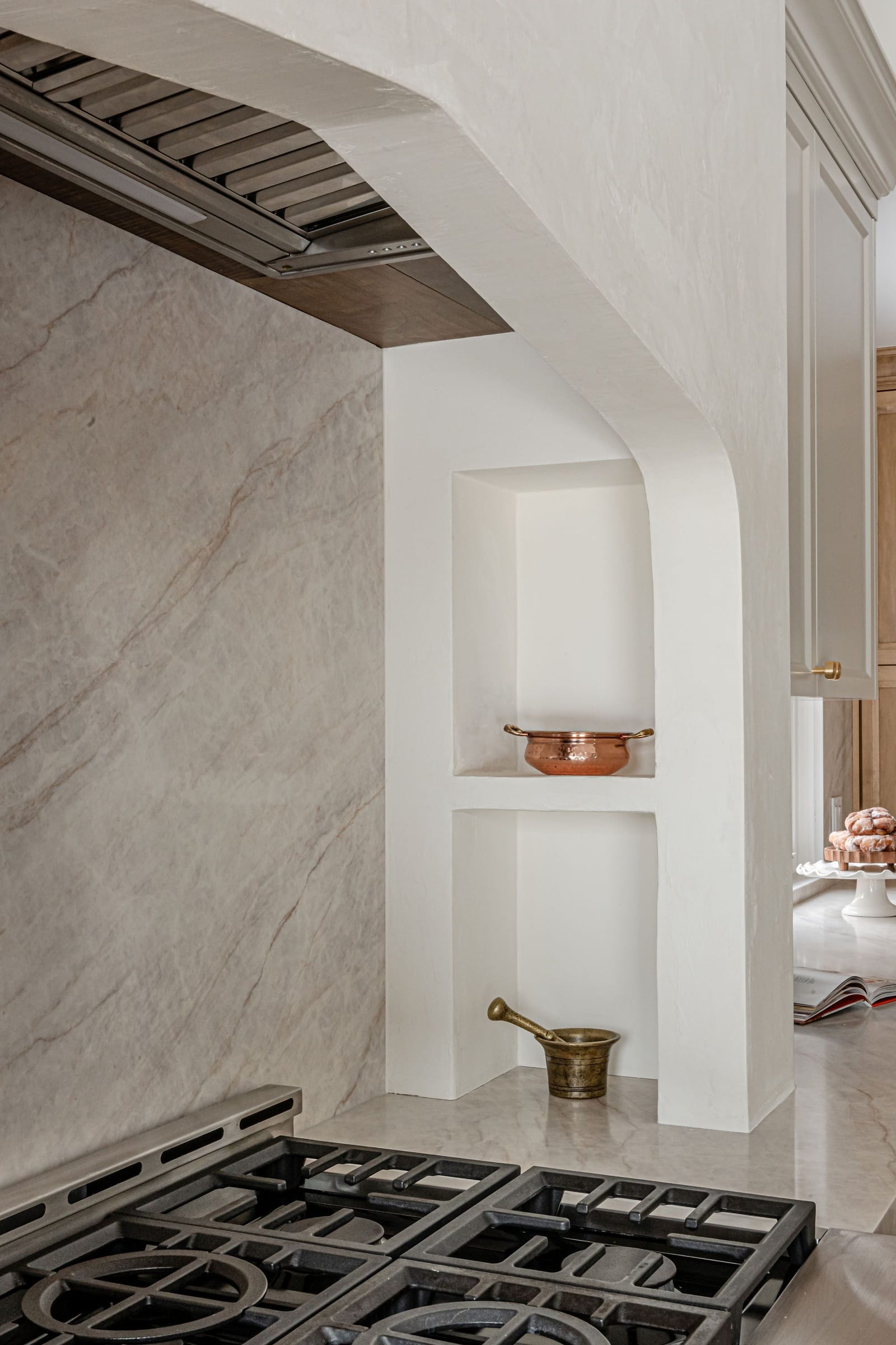 Close view of the arched plaster range alcove with built-in shelves and a stone backsplash