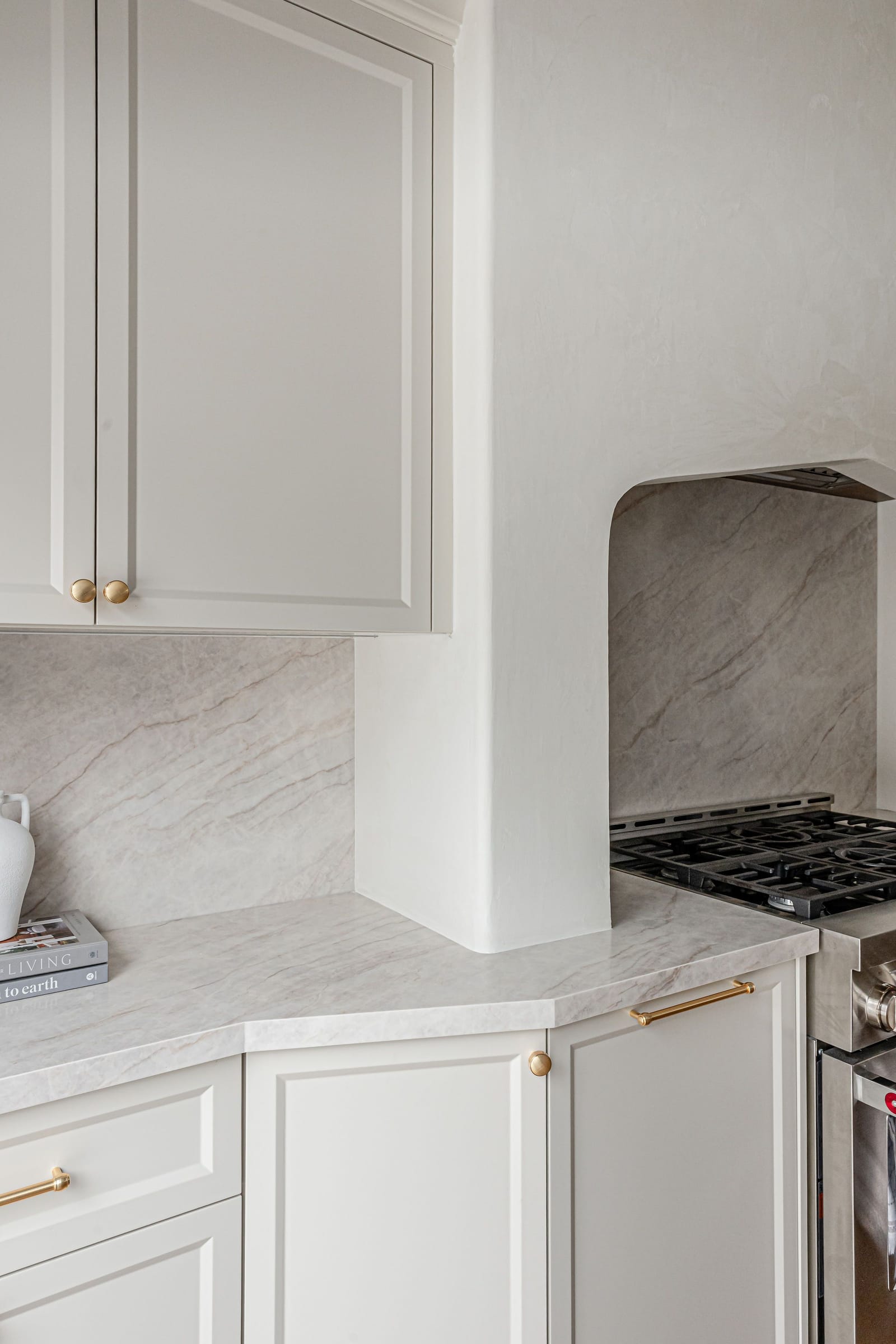 A cream cabinet corner with an angled counter beside the plaster range alcove