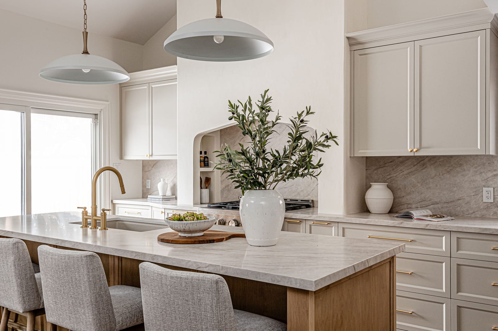 The island and range wall under two white dome pendants, with sliding doors to the yard