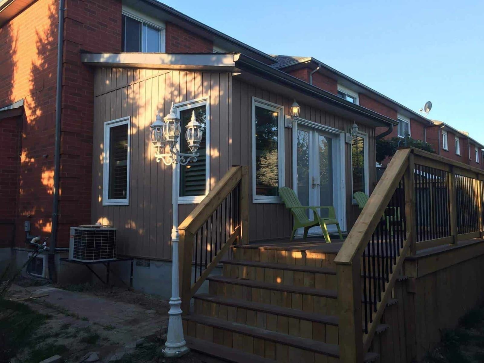 A rear addition in board and batten siding with French doors onto a new wooden deck and stairs