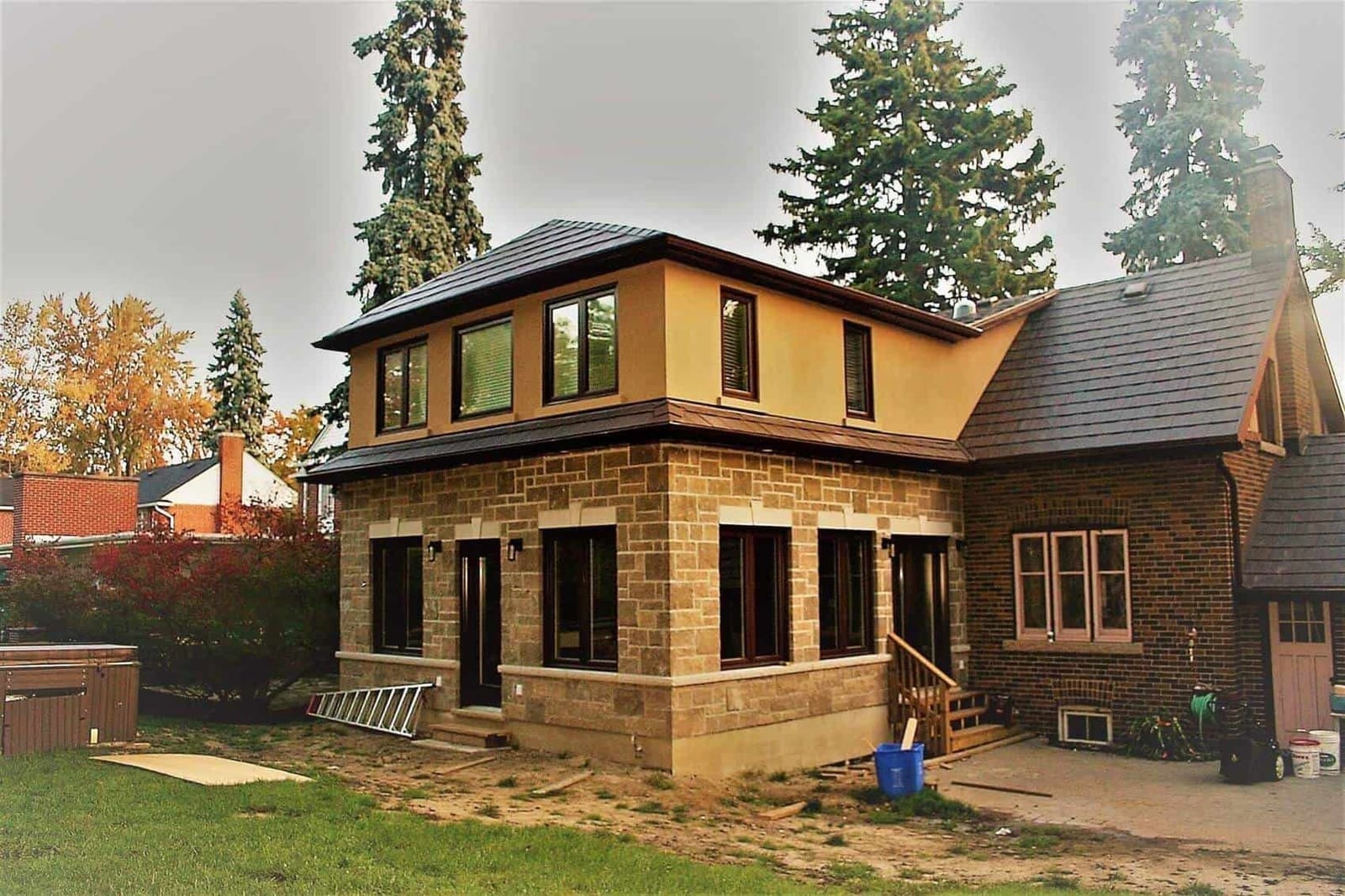 A two-storey rear addition with a cut-stone ground floor and a stucco upper floor, joined to an older brick house
