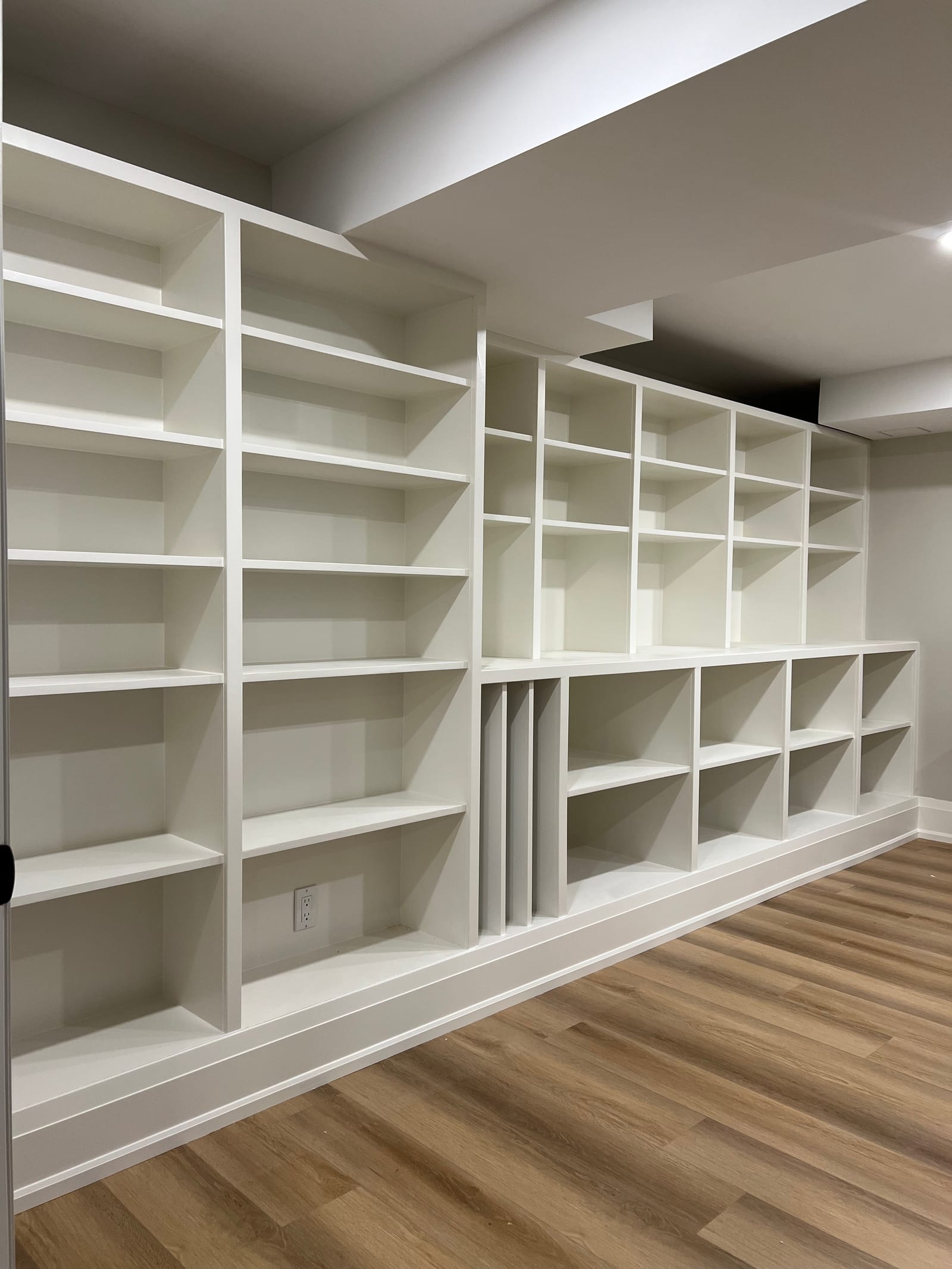 A wall of white built-in shelving in a basement room