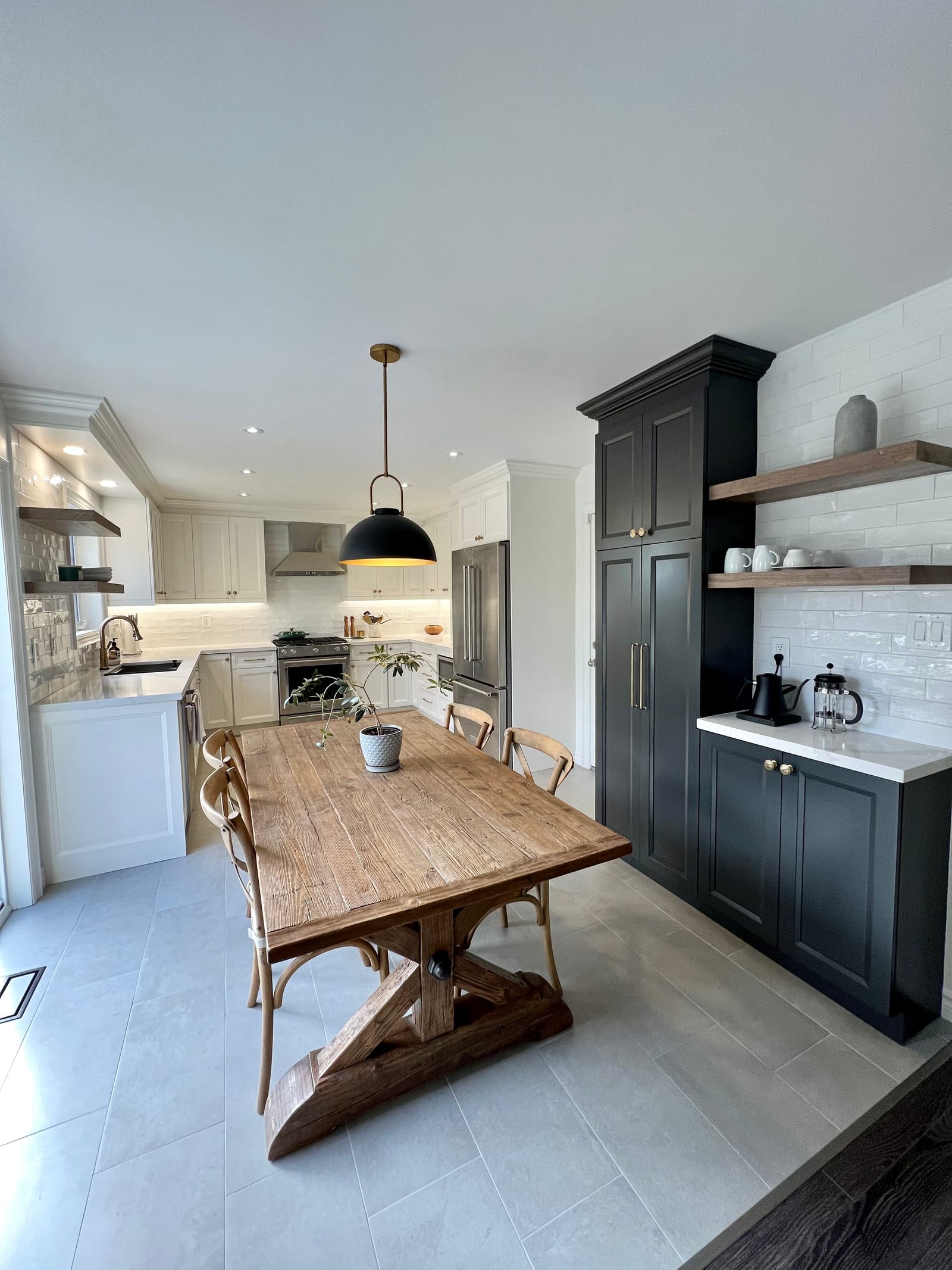 A charcoal pantry tower with floating walnut shelves and a coffee counter, beside a farmhouse table