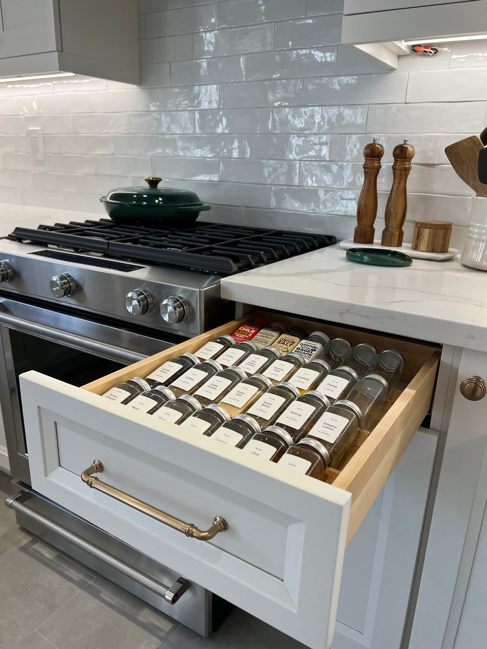 A spice drawer pulled out beside the range, with a brass bin pull