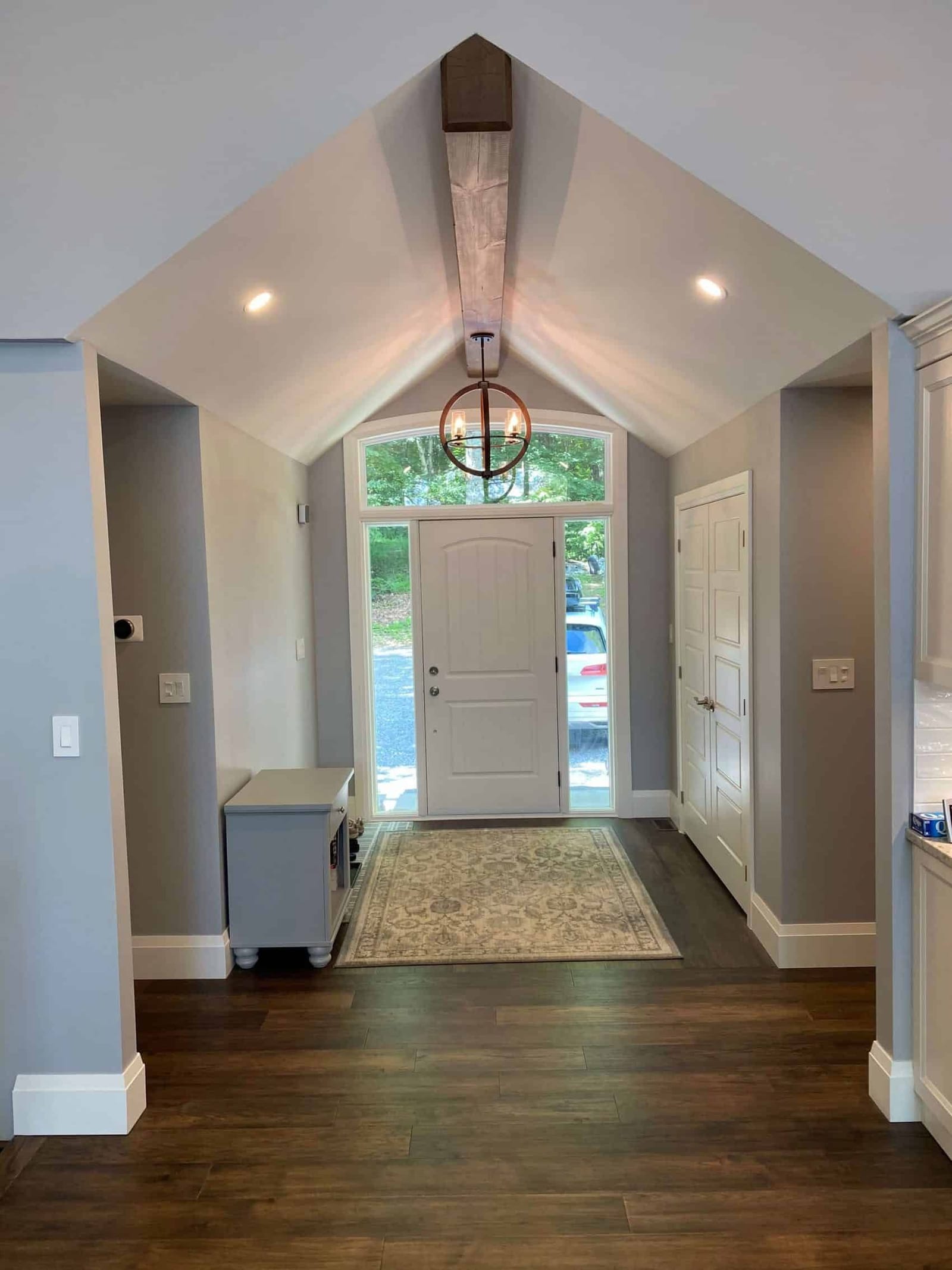 A vaulted foyer with a timber beam, an arched transom over the front door and a closet