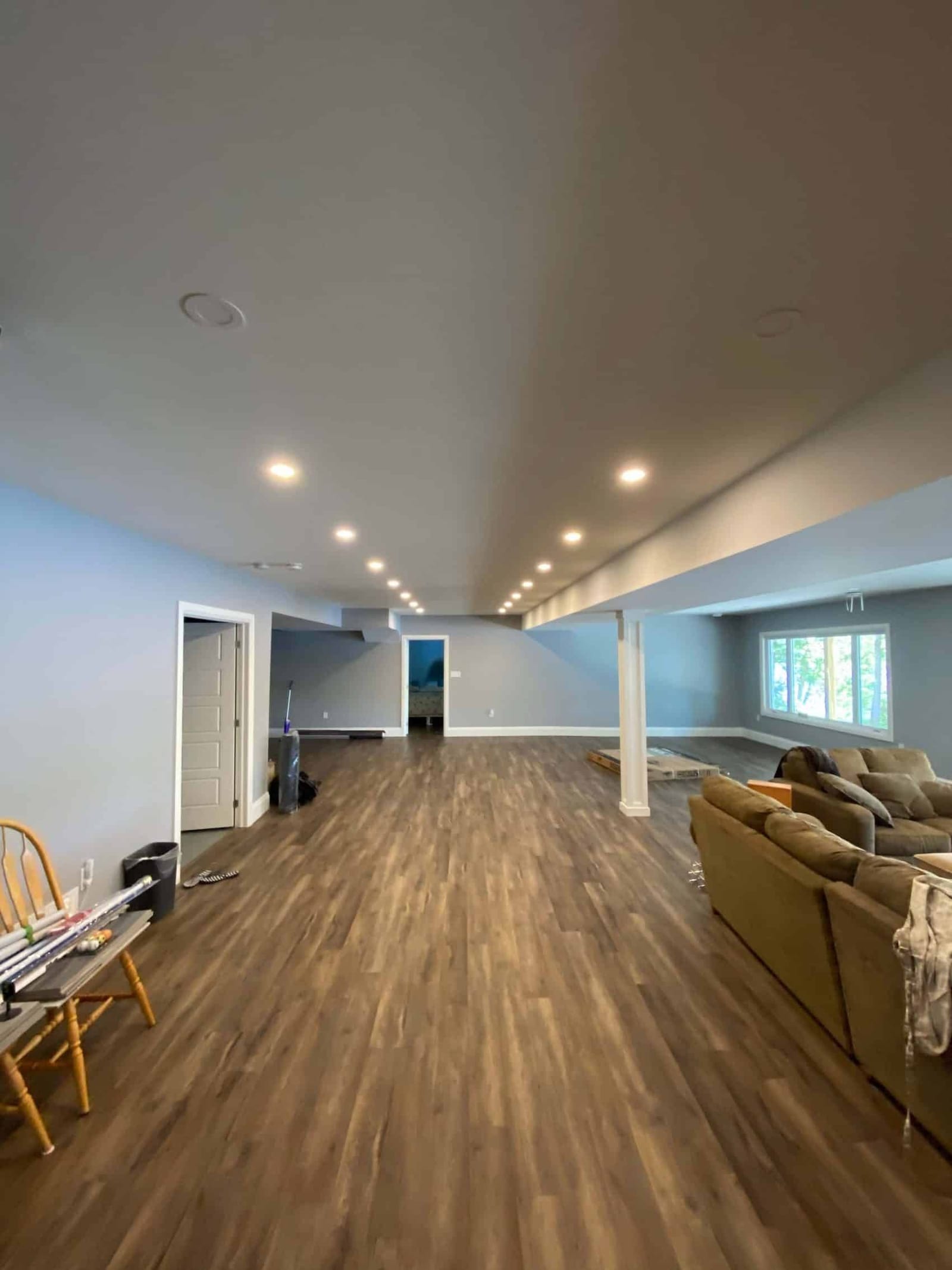 A long finished lower level with pot lights, a plank floor and a window at the far end