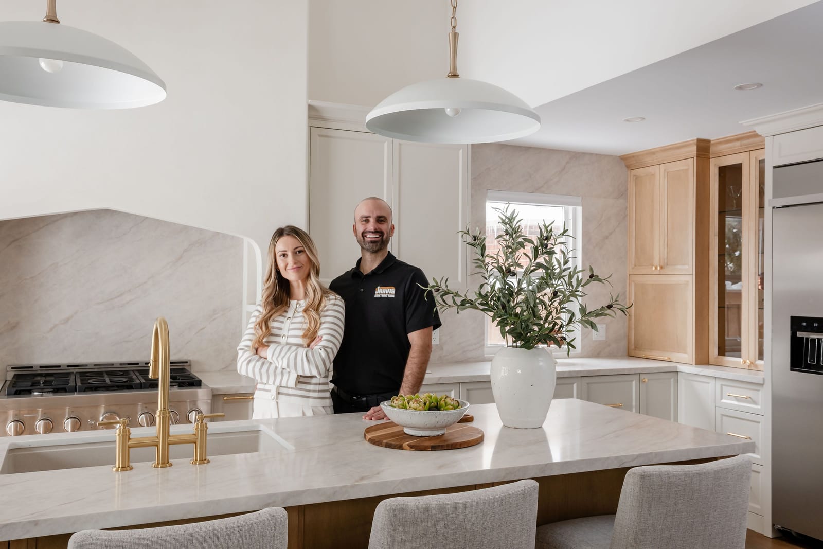 James Jarvis and Ceara standing together behind a stone kitchen island at Coventry Residence