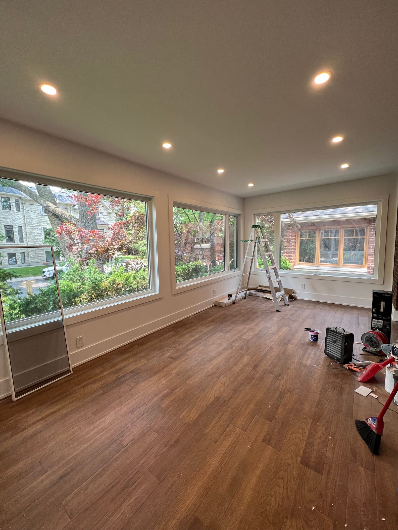 A newly finished room with wide windows on three sides and a plank floor, with tools still on site