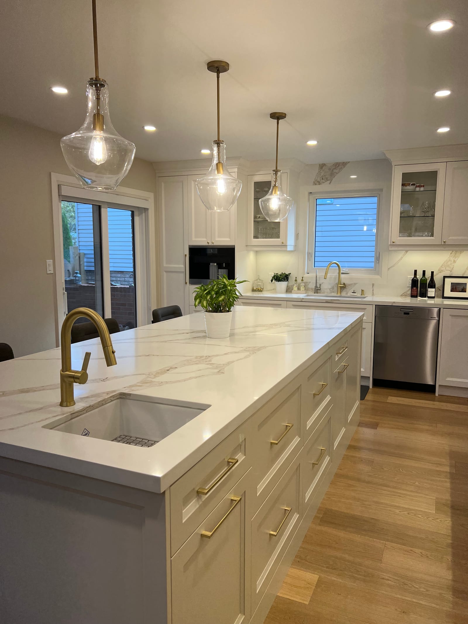 A long white island with a brass faucet and gold-veined top, running toward sliding doors