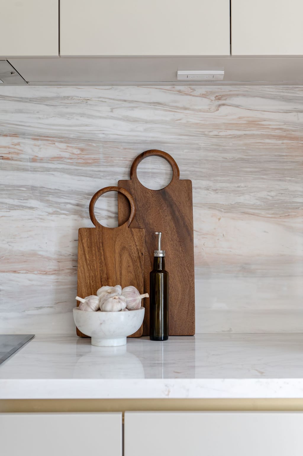 Close view of a pink, grey and cream veined stone backsplash with wooden boards and a brass-edged drawer below