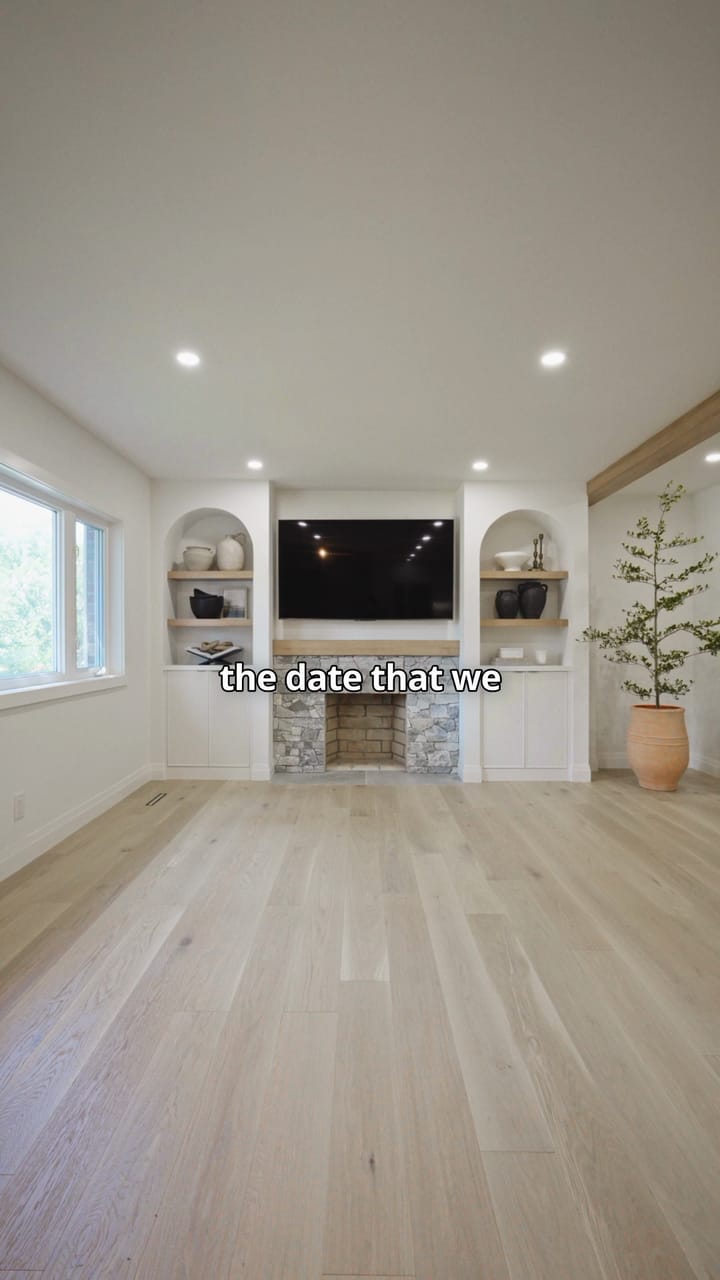 The Bellamy living room with a stacked stone fireplace between two arched built-ins under a mounted television