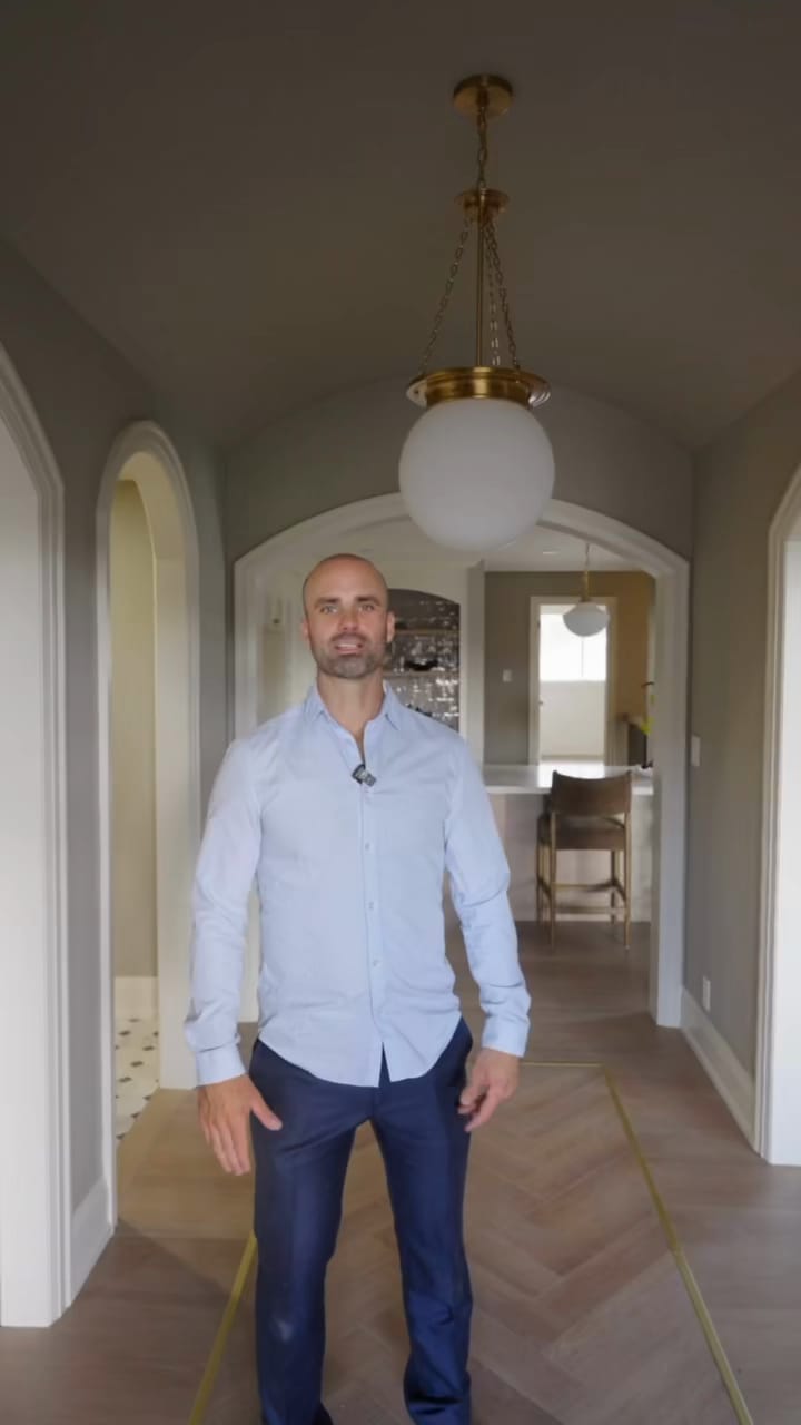 James Jarvis in an arched hallway under a barrel-vaulted ceiling and a brass globe pendant, with the kitchen through the arch behind him